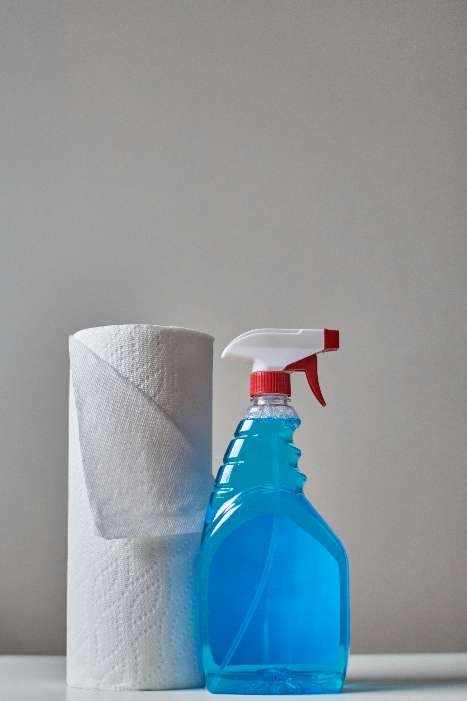 Blue spray bottle and paper towel ready for household cleaning